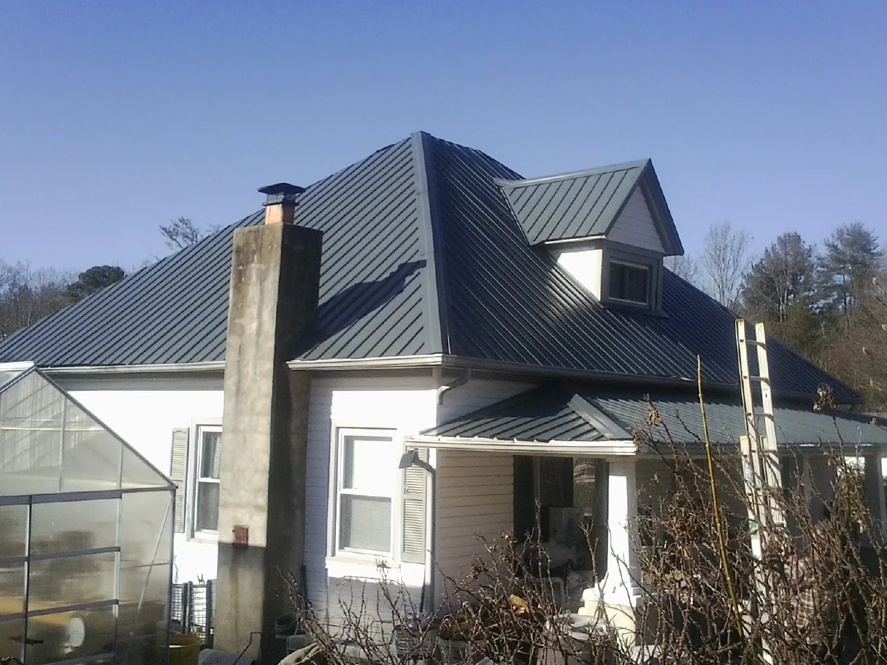 Dark blue standing seam metal roof on a white farmhouse with dormer — Slate & Tile Roof Repair by Roofing Brothers in Margaretville