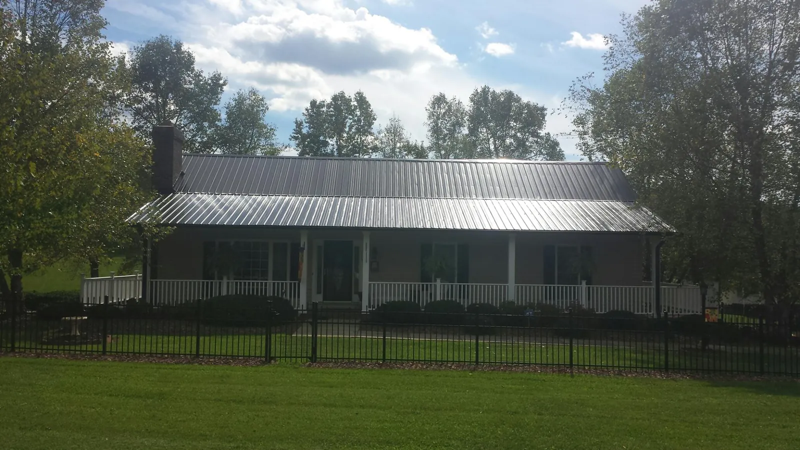 Gray metal roof on a brick ranch with a full width front porch — Gutter Guard Installation work by our crew in Margaretville