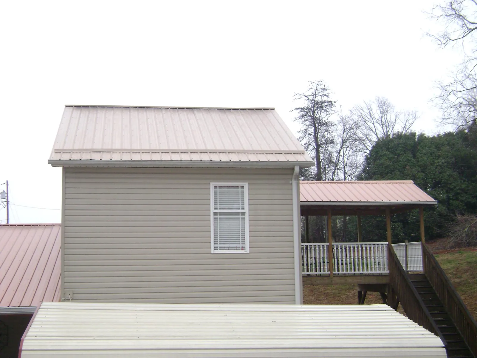 Tan metal roofs on a two story addition and attached porch, from a Roof Replacement job in Margaretville