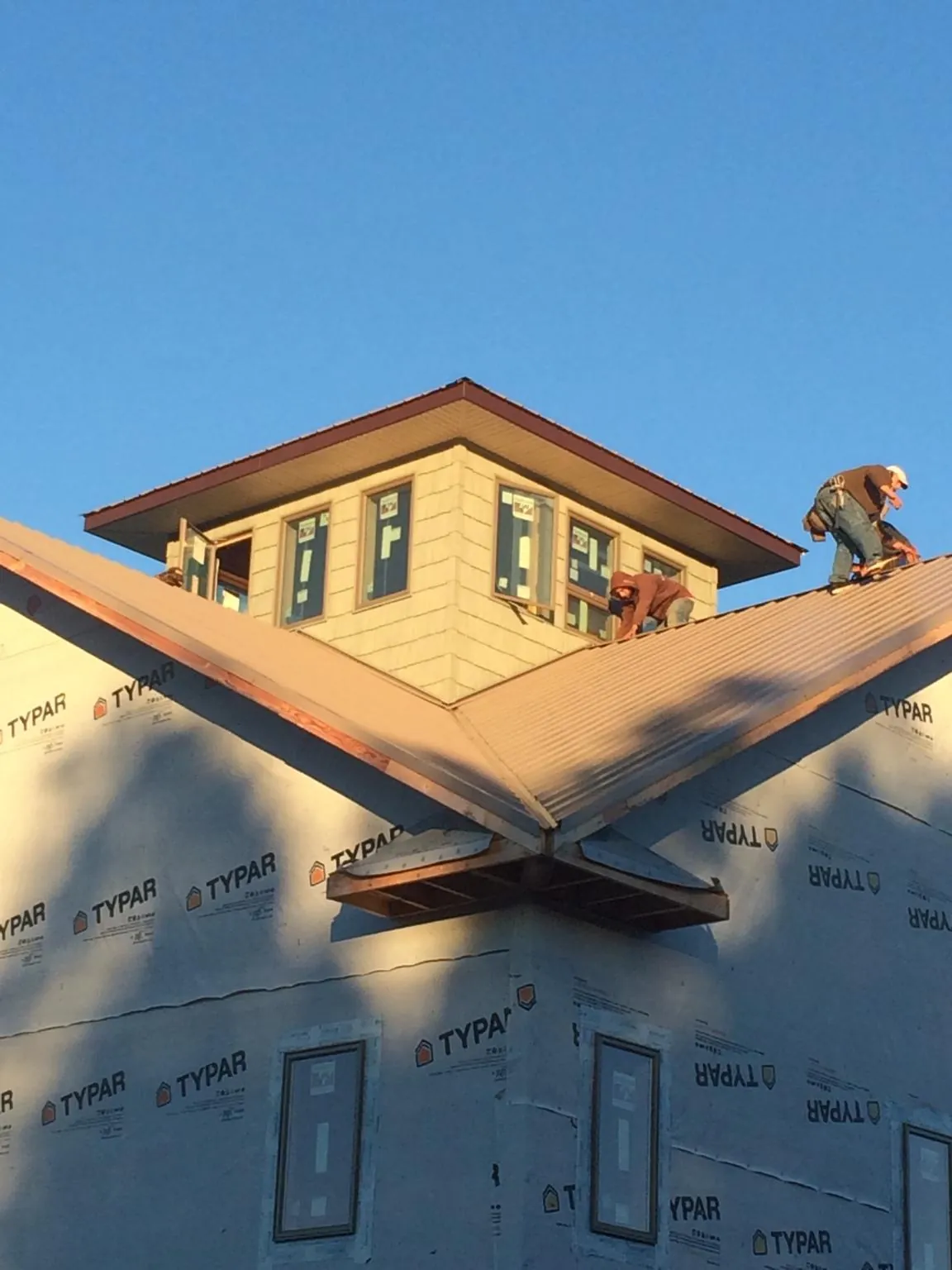 Roofers working around a rooftop cupola on a new metal roof at sunset — Roof Waterproofing in Margaretville by Roofing Brothers